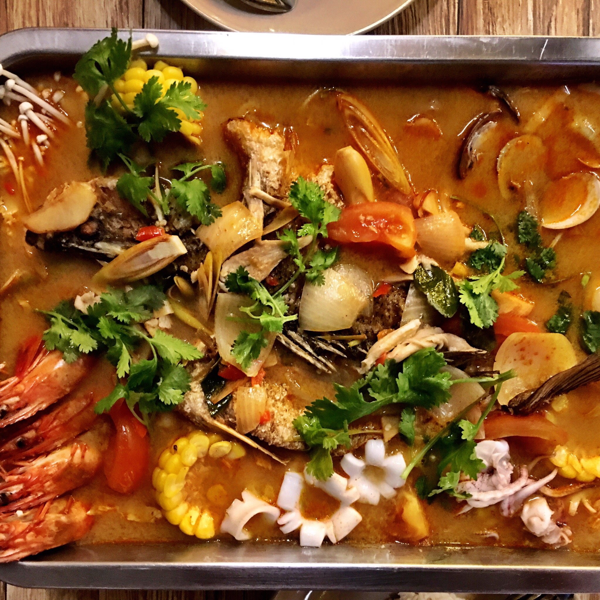 A vibrant red Tom Yam seafood pan with prawns, squid, fish and corn at Eat Drink Thai